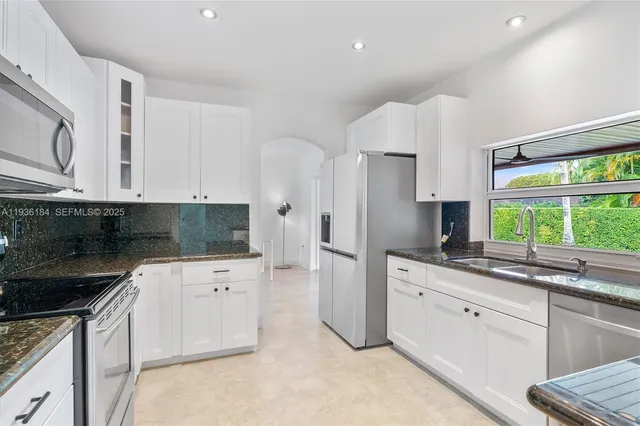 a kitchen with white cabinets and window