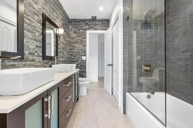 a bathroom with a granite countertop sink a toilet a bathtub and shower