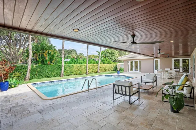 a view of a patio with chairs and table under an umbrella next to a yard