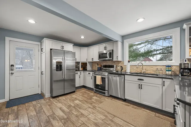 a kitchen with granite countertop a refrigerator and white cabinets