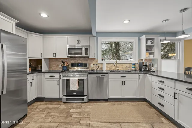 a kitchen with stainless steel appliances granite countertop a stove a sink and a refrigerator
