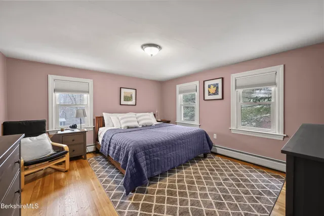 a spacious bedroom with a bed and wooden floor