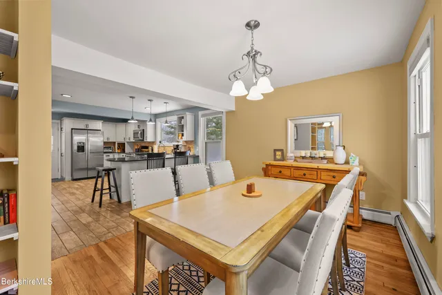a dining hall with stainless steel appliances kitchen island granite countertop furniture and chandelier