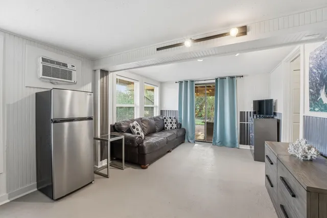 a living room with stainless steel appliances furniture refrigerator and a window