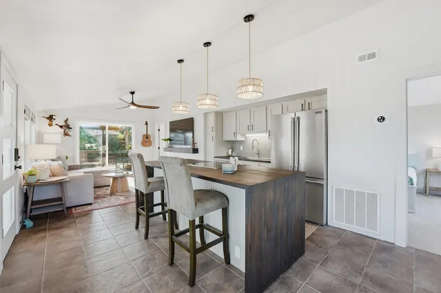 a kitchen with stainless steel appliances granite countertop a refrigerator a sink dishwasher a dining table and chairs with wooden floor