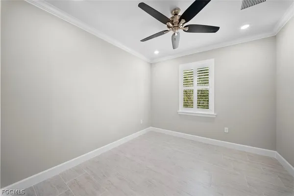 an empty room with ceiling fan and windows