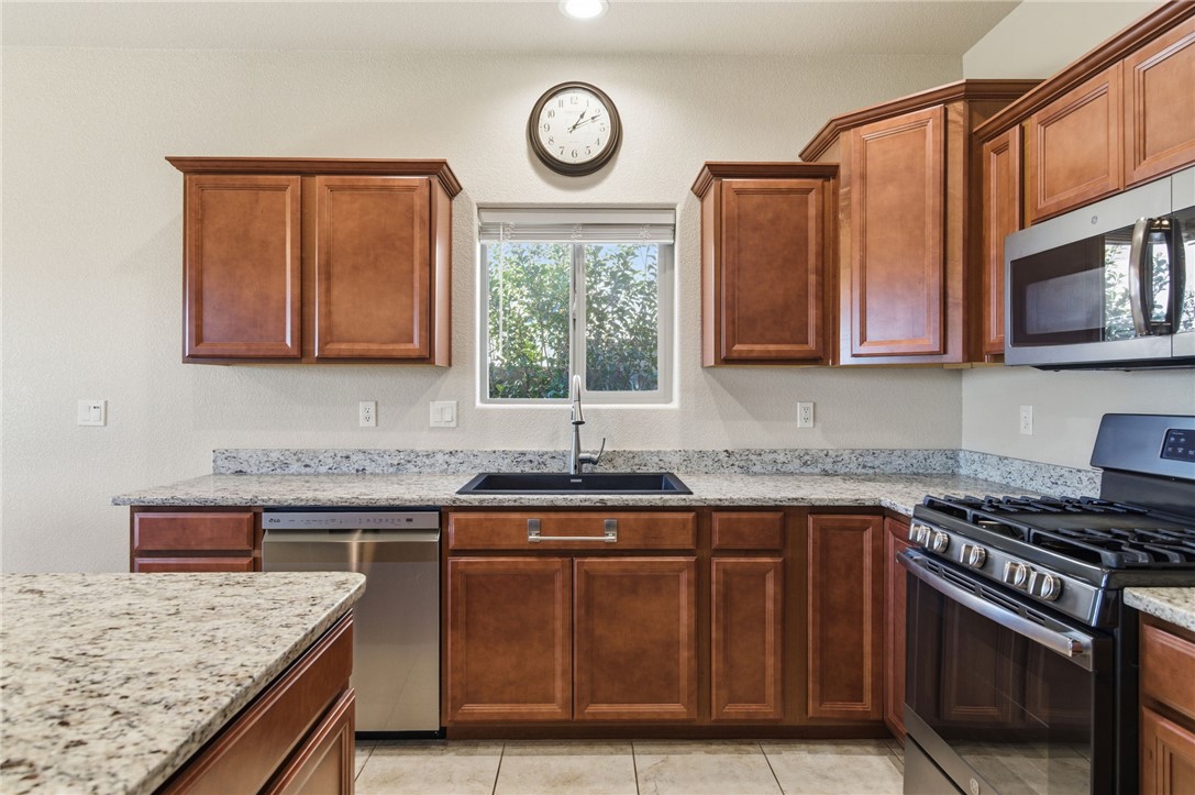 4745 East Old W Road Kingman, AZ 86401 - Photo 13 of 37 Kitchen with stainless steel appliances, light stone countertops, brown cabinets, and light tile patterned floors