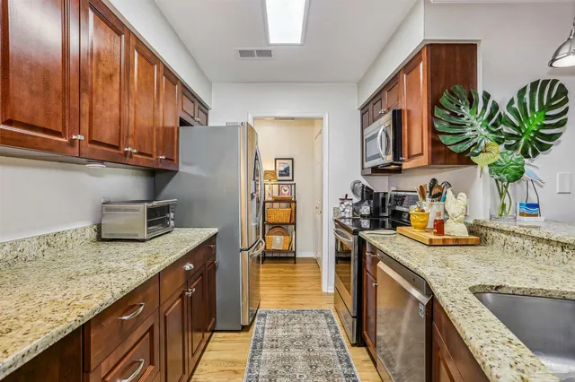 a kitchen with stainless steel appliances granite countertop a sink a stove and a wooden cabinets