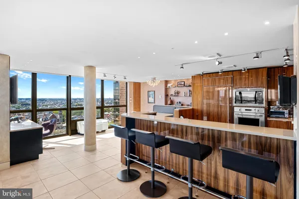 a large living room with stainless steel appliances kitchen island granite countertop a table chairs and a large window