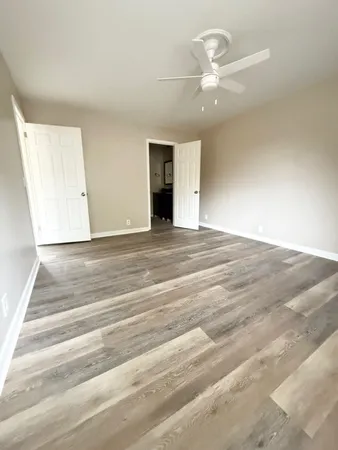 a view of an empty room with a ceiling fan and window