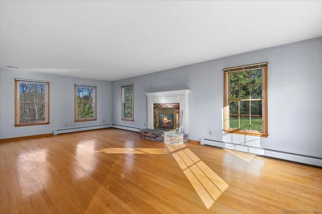 a view of an empty room with window and wooden floor