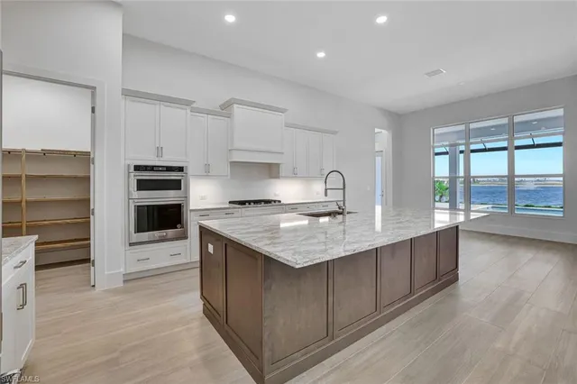 a kitchen with stainless steel appliances granite countertop a stove top oven a sink and a refrigerator