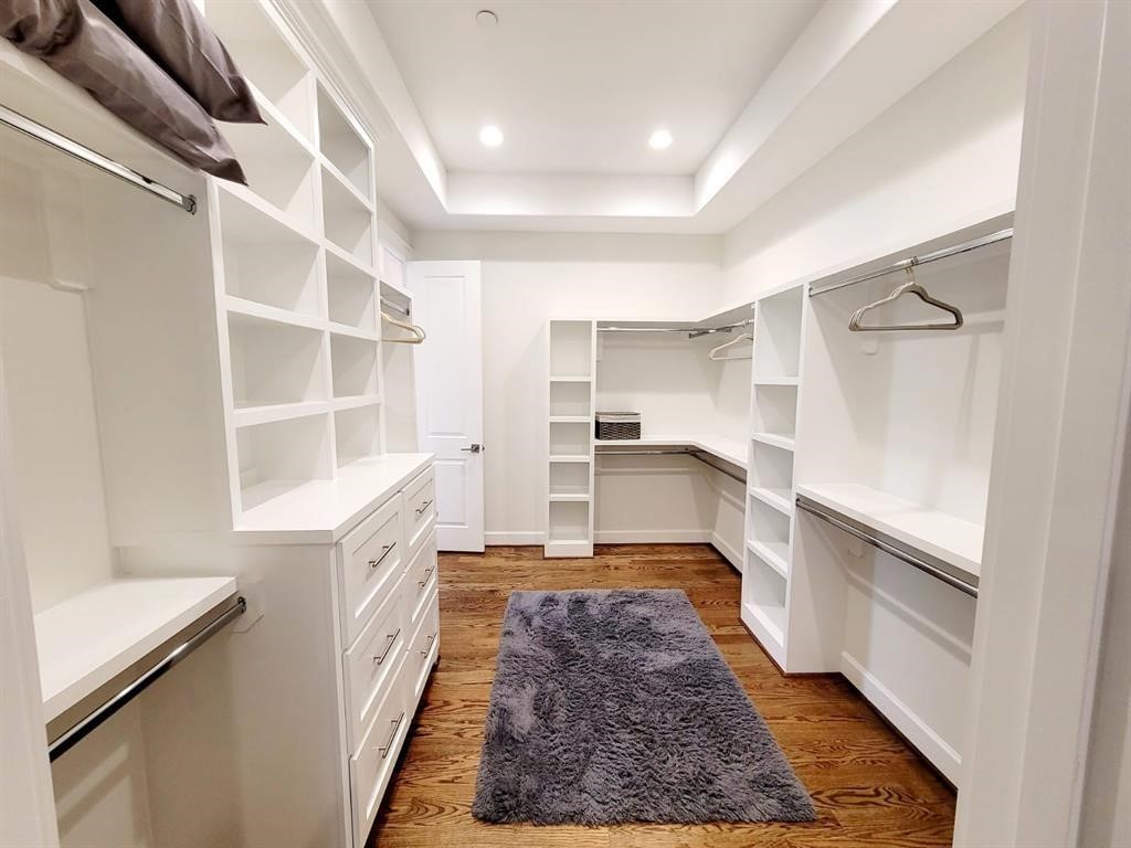 710 Delano Street, Unit A Houston, TX 77003 - Photo 9 of 32 Spacious walk-in closet featuring white shelving, drawers, and hanging racks, with hardwood flooring and recessed lighting. A cozy rug adds warmth.