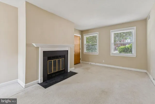 an empty room with windows and fireplace