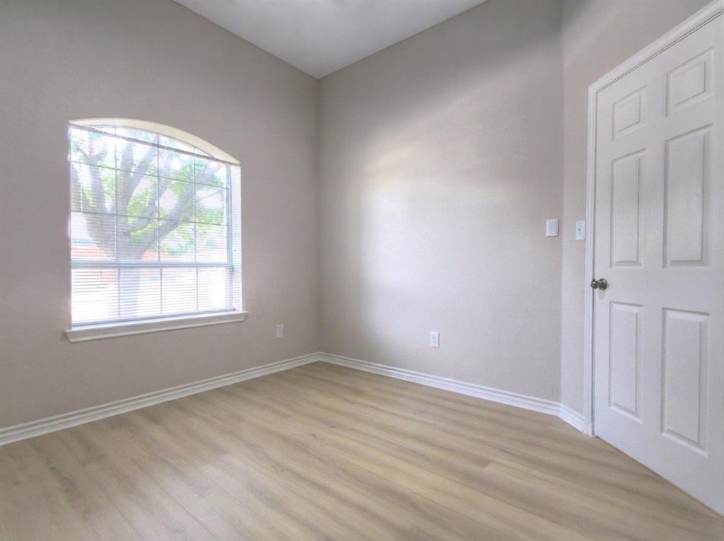 12000 Port Road Frisco, TX 75035 - Photo 31 of 40 Arched window with blinds, wood-finish flooring, light neutral wall color, white baseboards, and a paneled door