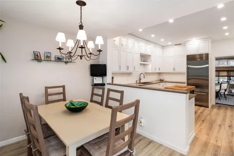 a kitchen with stainless steel appliances granite countertop a dining table chairs and white cabinets
