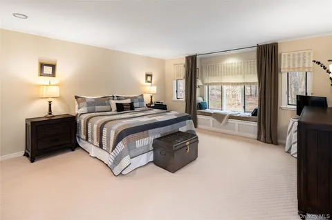 a spacious bedroom with a bed and a flat tv screen on the dresser