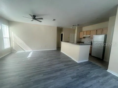 a view of a kitchen with wooden floor electronic appliances and cabinets