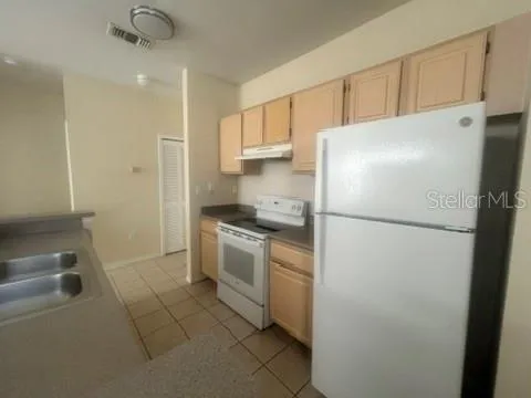 a white refrigerator freezer and a stove sitting inside of a kitchen