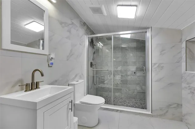 a bathroom with a shower sink vanity mirror and toilet