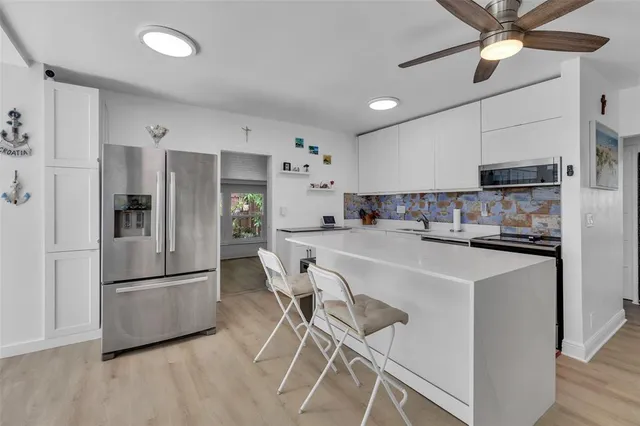 a kitchen with stainless steel appliances a refrigerator a sink dishwasher a stove and a refrigerator with wooden floor