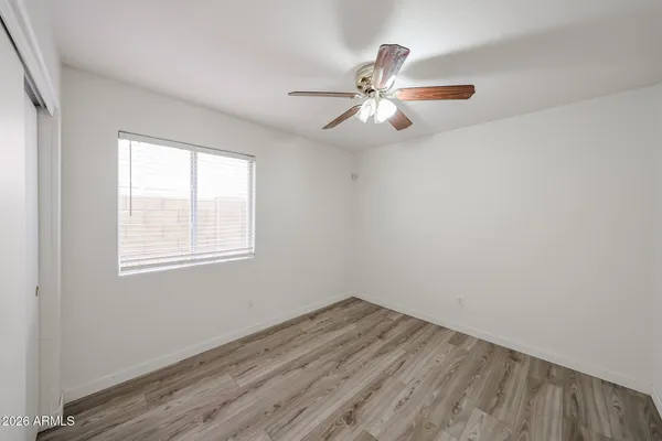 a view of empty room with wooden floor and fan