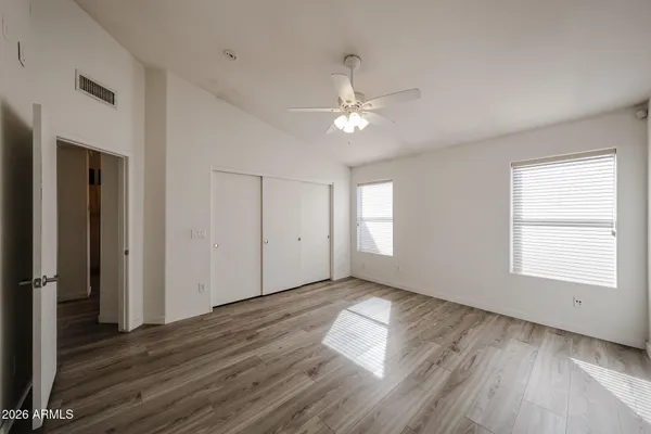 an empty room with wooden floor chandelier fan and windows