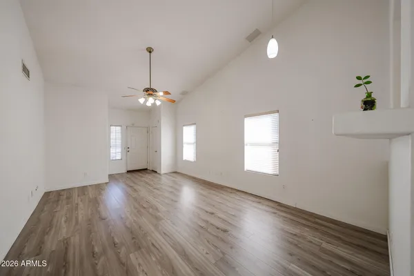 a view of empty room with wooden floor and fan