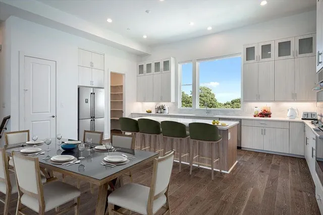 a kitchen with a dining table chairs and refrigerator