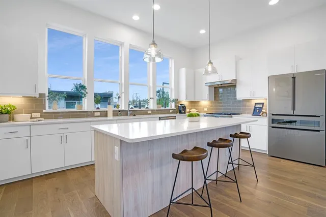 a kitchen with kitchen island granite countertop a table chairs stove and refrigerator
