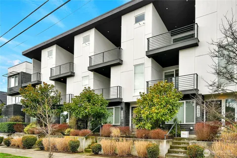 a view of a house with a barbeque and large trees