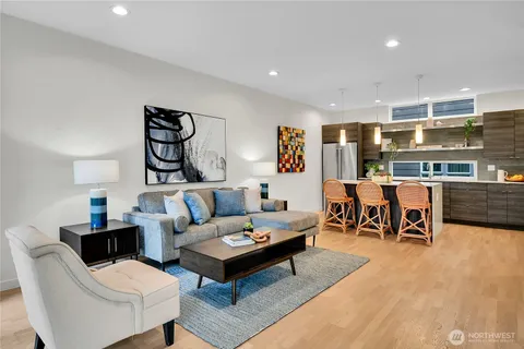 a kitchen with stainless steel appliances kitchen island granite countertop a stove top oven a sink a dining table and chairs with wooden floor