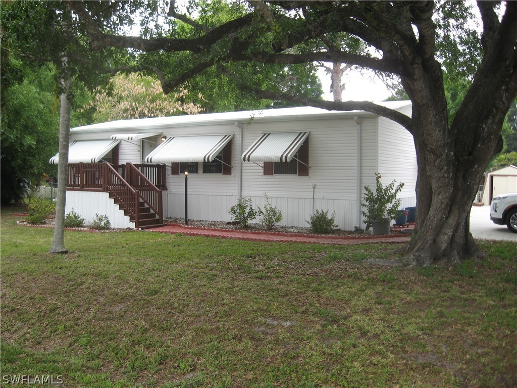 a view of a white house with a large tree and a yard