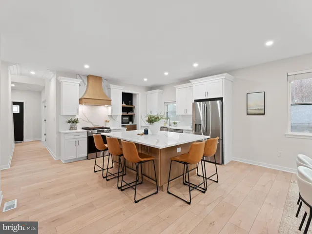 a kitchen with stainless steel appliances granite countertop a stove a refrigerator a sink a dining table and chairs with wooden floor