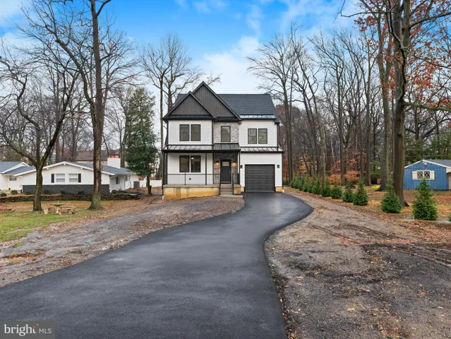 a view of a white house next to a road with large trees