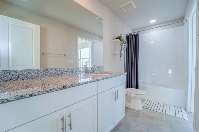 a bathroom with a granite countertop sink a toilet and a bathtub