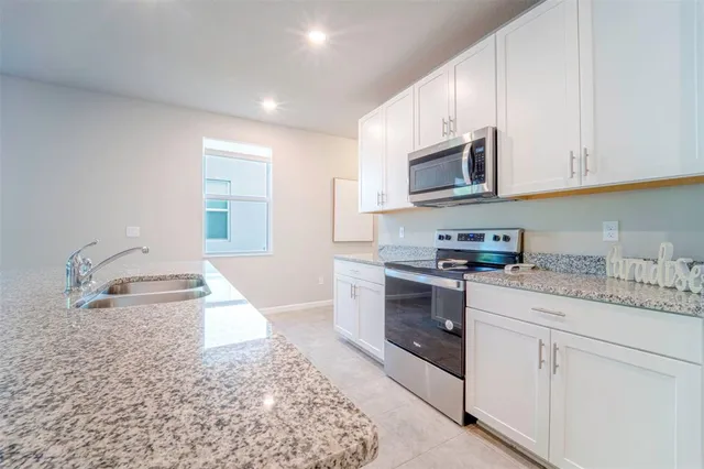 a kitchen with granite countertop a sink a stove and cabinets