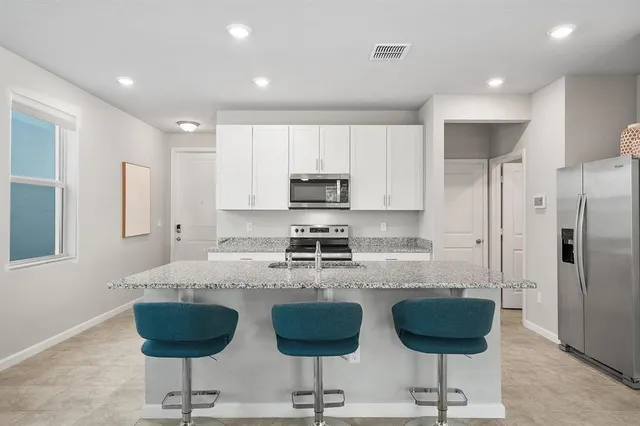 a kitchen with granite countertop a refrigerator and a stove top oven with wooden floor