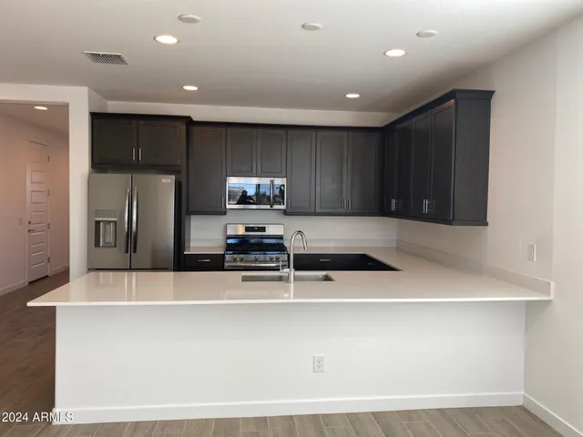 a kitchen with stainless steel appliances a refrigerator a sink a stove a microwave and island