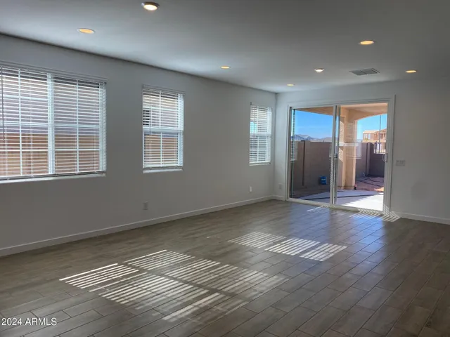a view of an empty room with wooden floor and windows