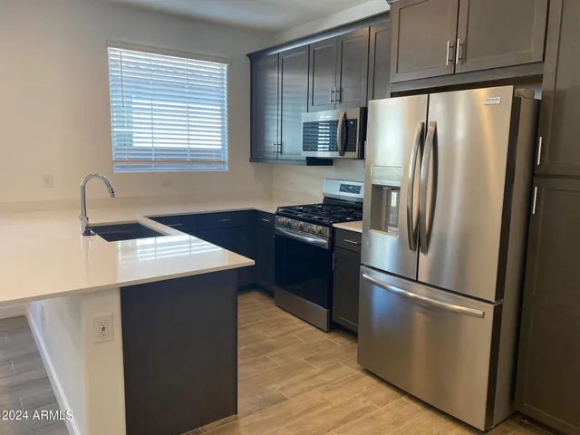 a kitchen with metallic refrigerator and wooden cabinets