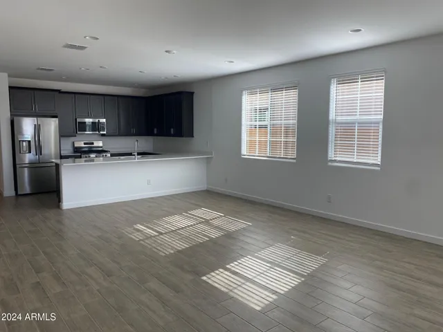 a kitchen with stainless steel appliances granite countertop a stove top oven a sink dishwasher and a refrigerator with wooden floor