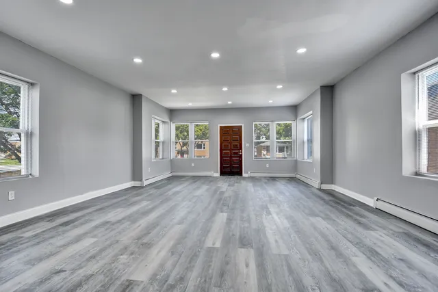a view of an empty room with a window and wooden floor