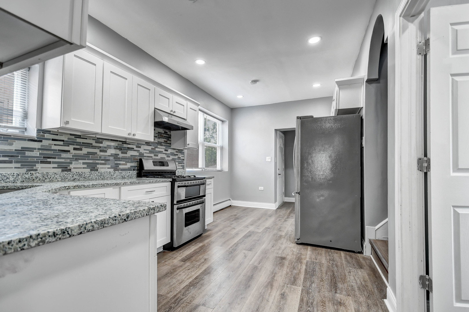 7409 West 63rd Place Summit, IL 60501 - Photo 4 of 18 a kitchen with stainless steel appliances granite countertop a refrigerator a stove and a sink with wooden floor