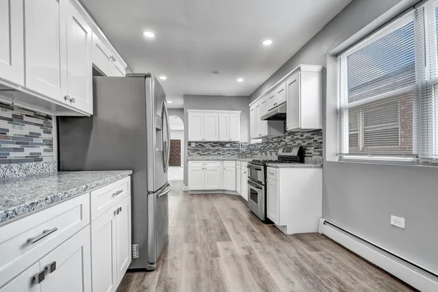 a kitchen with a refrigerator and white cabinets