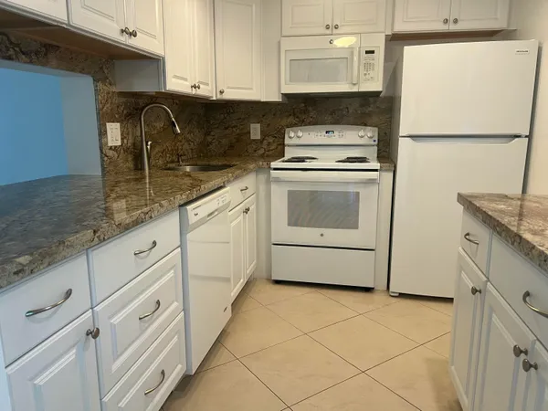 a kitchen with granite countertop white cabinets and white appliances