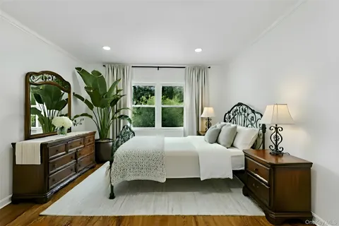 a bedroom with a bed table flowerpot and window