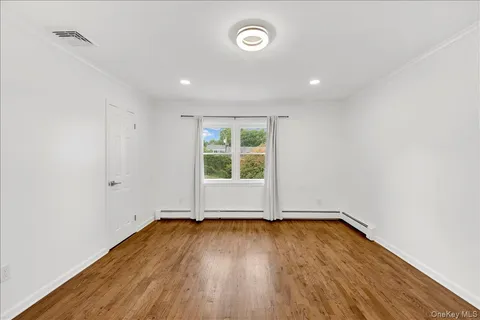 an empty room with wooden floor and window