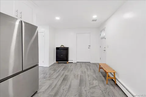 a view of an empty room with wooden floor and a refrigerator