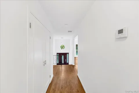 a view of a hallway to an empty room with wooden floor and a window